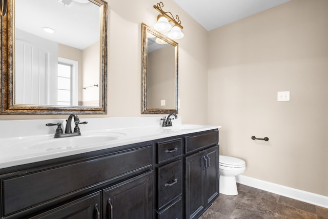 full bath with a sink, baseboards, toilet, and double vanity