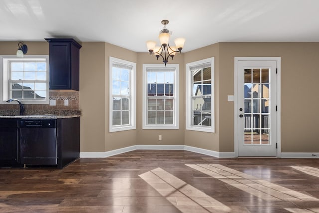 unfurnished dining area with baseboards, dark wood-type flooring, an inviting chandelier, and a sink