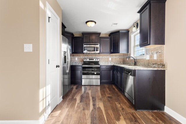 kitchen with a sink, dark wood finished floors, tasteful backsplash, and stainless steel appliances