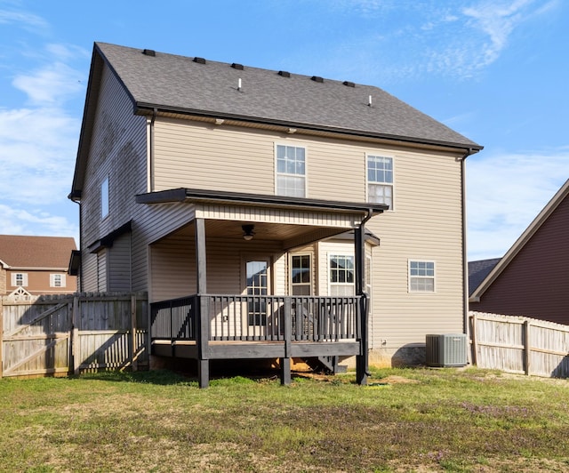 rear view of house featuring fence, roof with shingles, cooling unit, a deck, and a yard