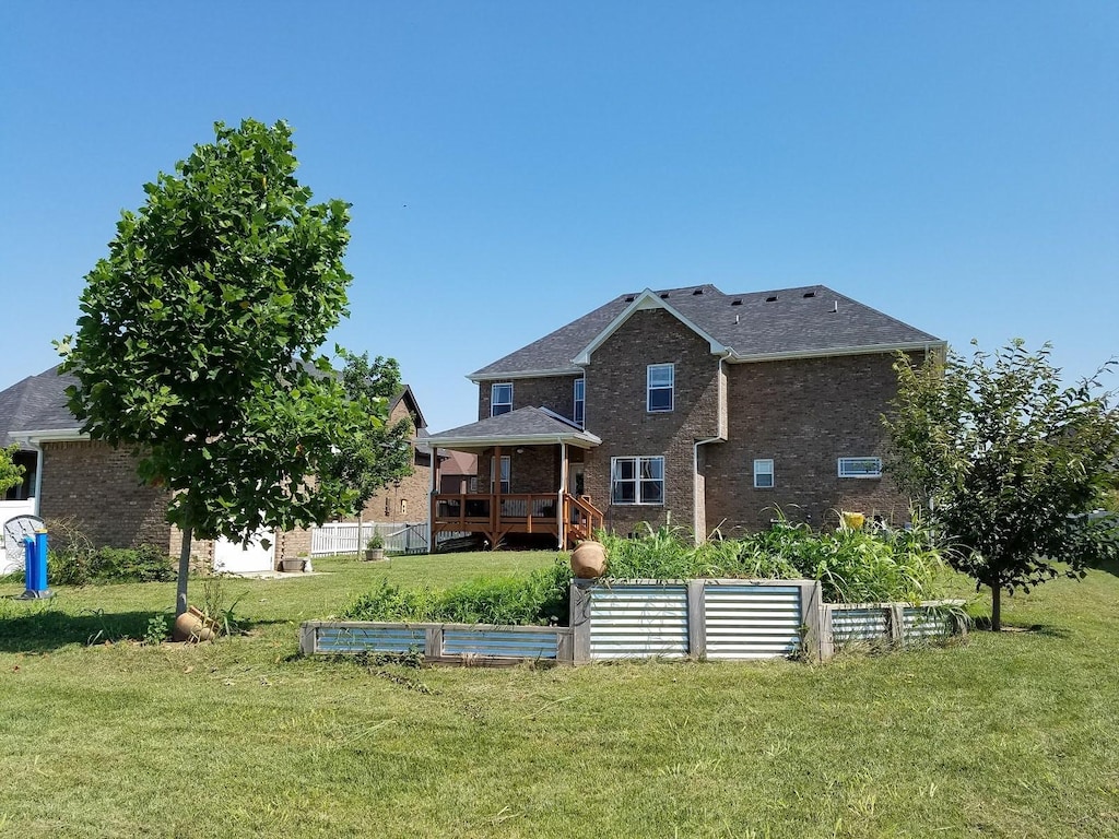 view of front of house with brick siding, a front lawn, and a vegetable garden