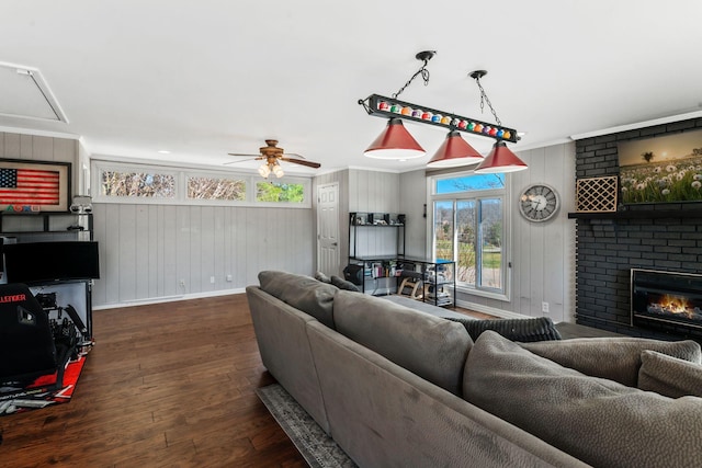 living area with crown molding, attic access, a fireplace, wood finished floors, and a ceiling fan