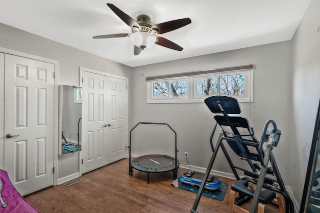 workout area with visible vents, baseboards, wood finished floors, and a ceiling fan