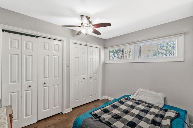 bedroom featuring ceiling fan, baseboards, multiple closets, and dark wood-style floors