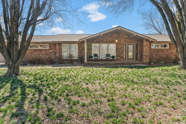 view of front of property with a front lawn, a patio area, and brick siding