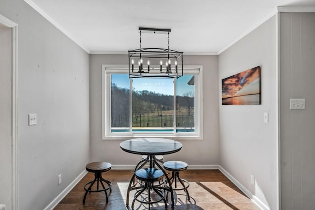 dining area featuring crown molding, wood finished floors, baseboards, and a chandelier