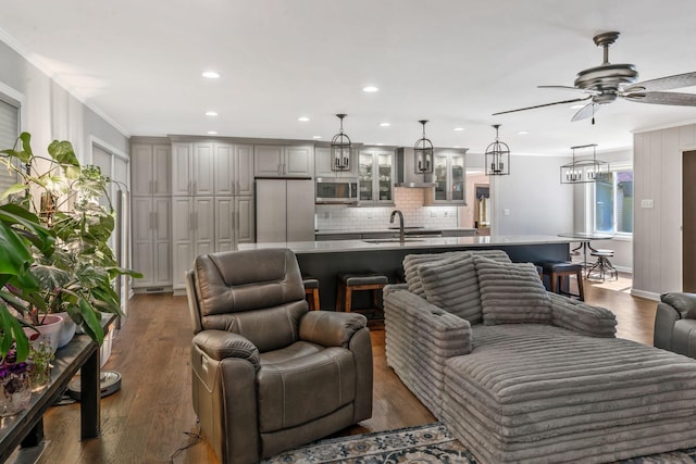 living room with recessed lighting, ceiling fan with notable chandelier, ornamental molding, and wood finished floors