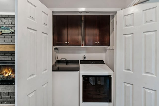 laundry area featuring washer and dryer, a brick fireplace, and cabinet space