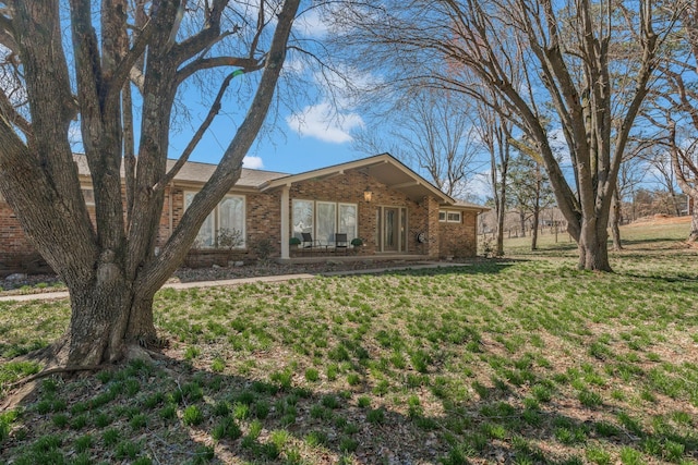 rear view of house featuring brick siding and a lawn