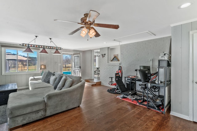 living room featuring attic access, wood finished floors, brick wall, and ceiling fan