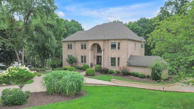 view of front of home featuring a front lawn, brick siding, and a shingled roof