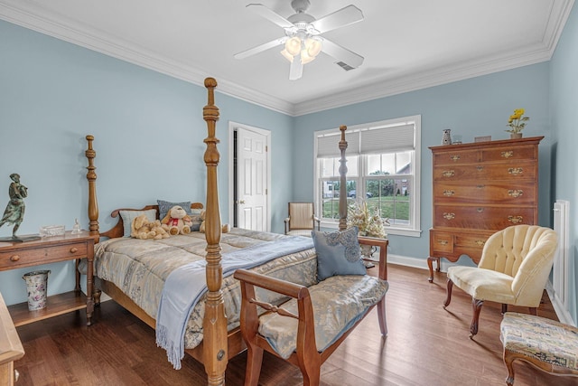 bedroom with visible vents, crown molding, baseboards, wood finished floors, and a ceiling fan