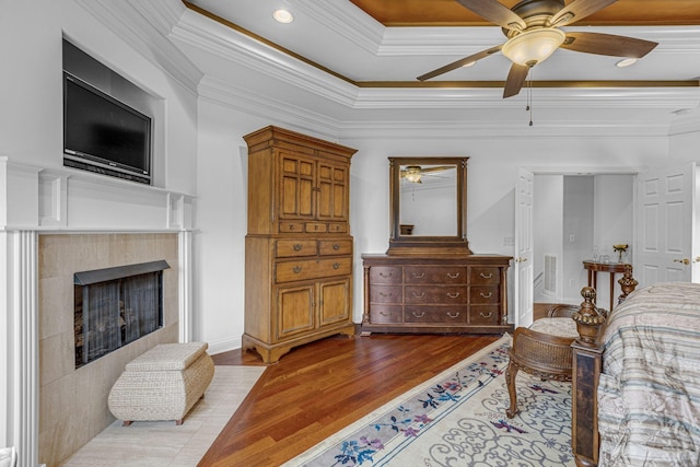 bedroom with crown molding, recessed lighting, a tile fireplace, wood finished floors, and a ceiling fan