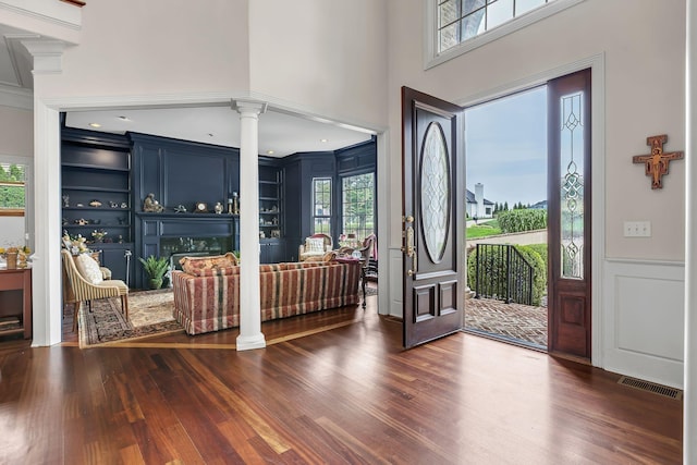 foyer featuring dark wood-type flooring, decorative columns, visible vents, and plenty of natural light