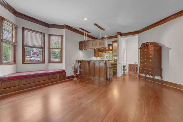 interior space with a wealth of natural light, a peninsula, wood finished floors, and crown molding