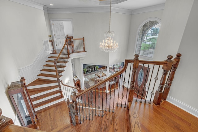 stairs featuring visible vents, a notable chandelier, wood finished floors, crown molding, and baseboards