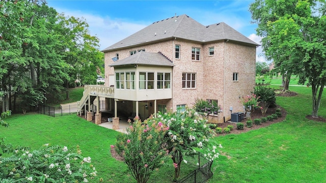 back of property with fence, central air condition unit, a wooden deck, a yard, and a patio