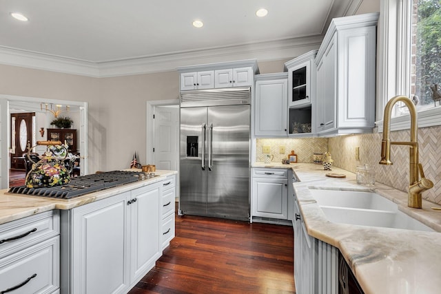 kitchen with a sink, appliances with stainless steel finishes, white cabinets, crown molding, and dark wood-style flooring