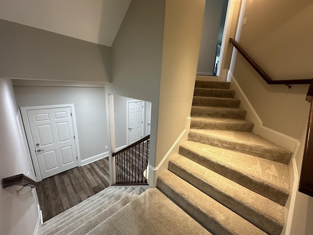 stairs with baseboards, high vaulted ceiling, and wood finished floors