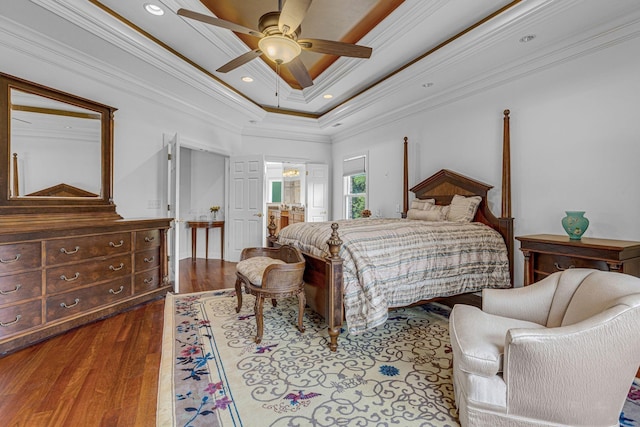 bedroom with wood finished floors, recessed lighting, crown molding, a raised ceiling, and ceiling fan