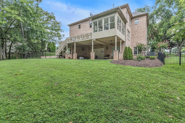 rear view of house featuring stairway, a lawn, a fenced backyard, and brick siding