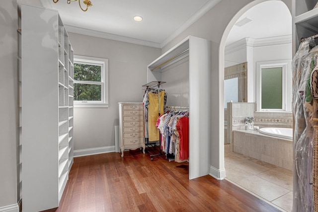 walk in closet with arched walkways, visible vents, and wood finished floors