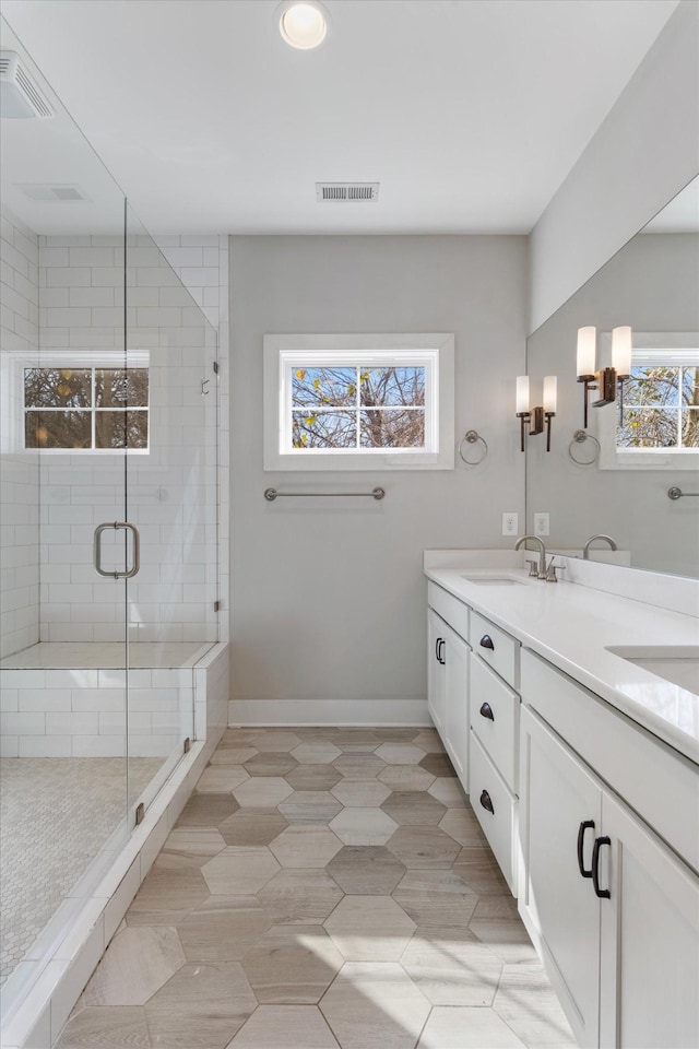 full bath with a shower stall, baseboards, a wealth of natural light, and a sink