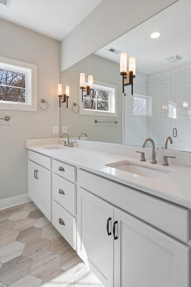 full bath with visible vents, a stall shower, and a sink