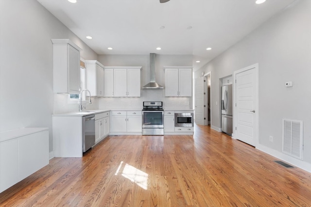 kitchen featuring tasteful backsplash, visible vents, wall chimney range hood, stainless steel appliances, and a sink