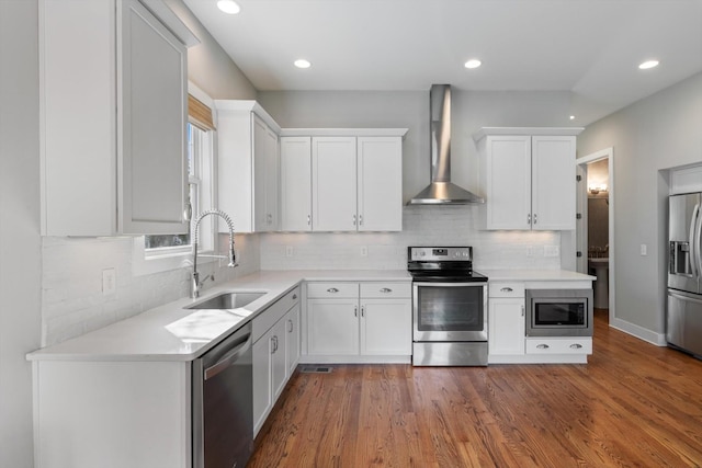 kitchen featuring a sink, wall chimney range hood, white cabinetry, stainless steel appliances, and light countertops