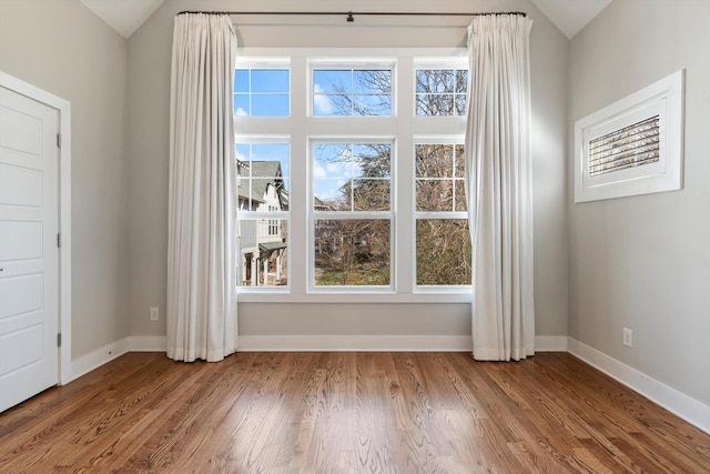 unfurnished room featuring lofted ceiling, wood finished floors, and baseboards