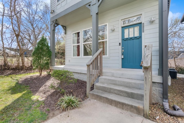 view of exterior entry featuring central air condition unit and covered porch