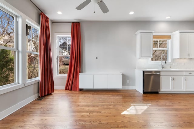 unfurnished dining area with baseboards, light wood-type flooring, a ceiling fan, and a sink