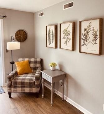 living area featuring visible vents, baseboards, and wood finished floors