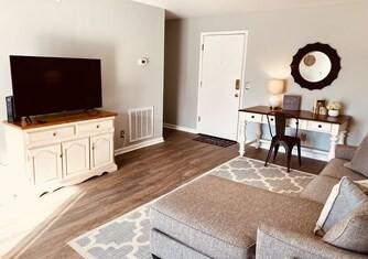 living area featuring wood finished floors, visible vents, and baseboards