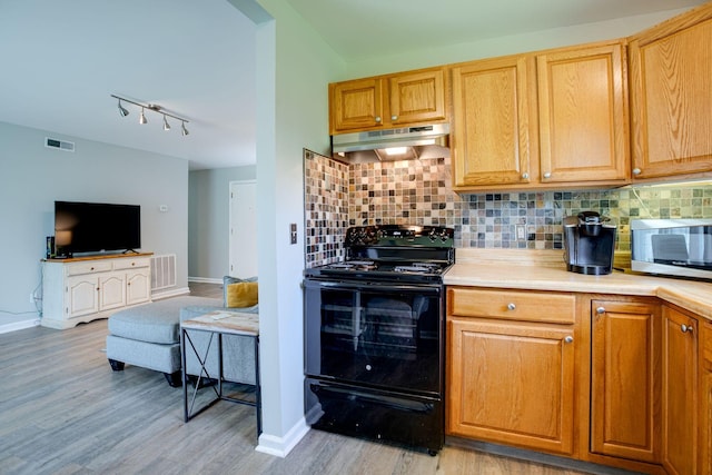 kitchen with baseboards, black / electric stove, under cabinet range hood, and visible vents