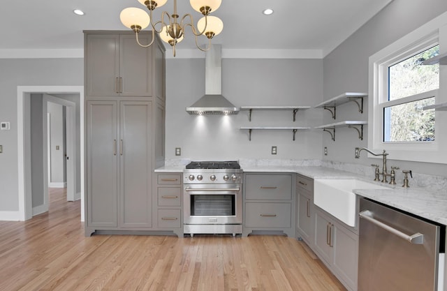 kitchen with a sink, gray cabinetry, wall chimney range hood, appliances with stainless steel finishes, and open shelves