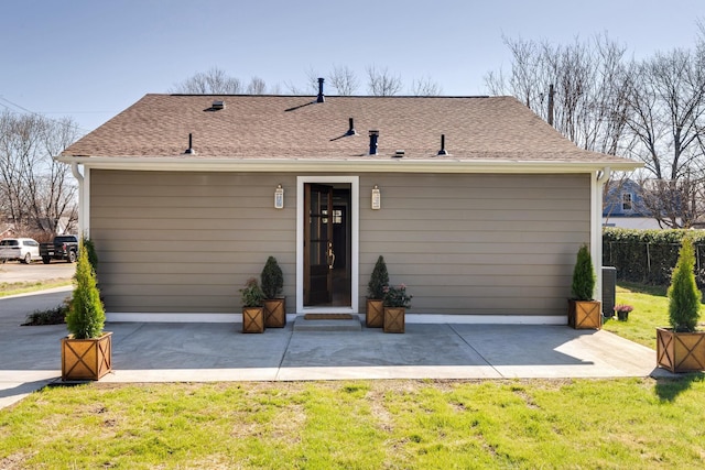 view of front of property featuring a patio area, roof with shingles, a front lawn, and fence