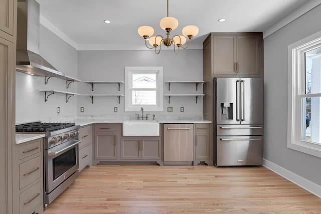 kitchen with a notable chandelier, open shelves, a sink, wall chimney range hood, and high end appliances