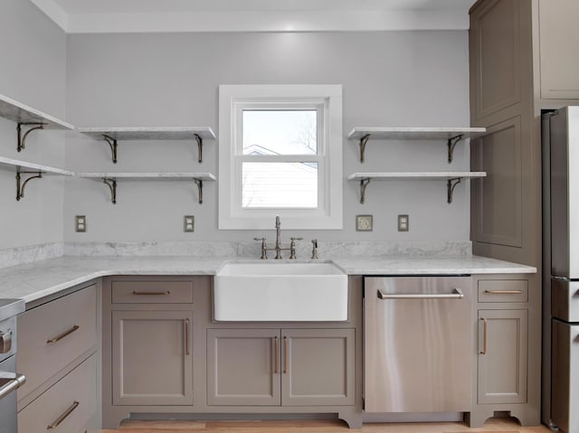 kitchen with light stone counters, open shelves, gray cabinets, a sink, and appliances with stainless steel finishes