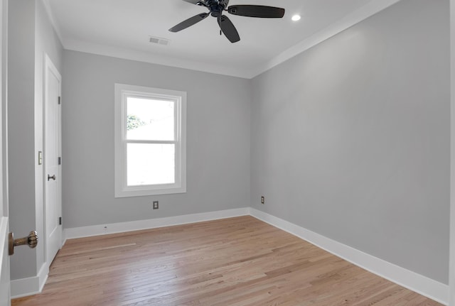 spare room with visible vents, a ceiling fan, light wood-style floors, crown molding, and baseboards