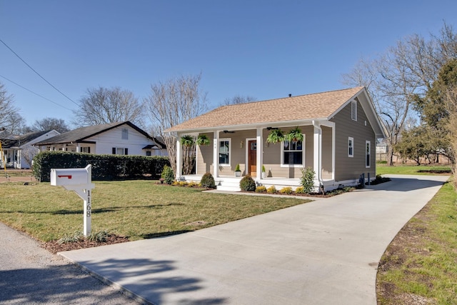 view of front of home with a ceiling fan, driveway, covered porch, a shingled roof, and a front lawn