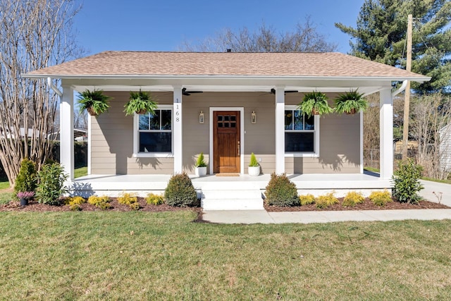 view of front facade featuring roof with shingles, covered porch, and a front yard