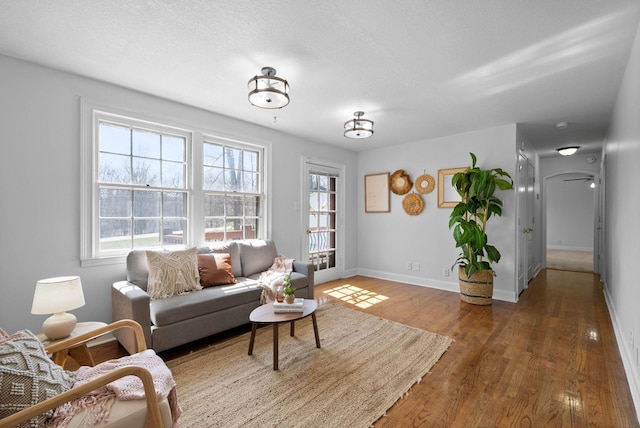 living room with a healthy amount of sunlight, a textured ceiling, baseboards, and wood finished floors