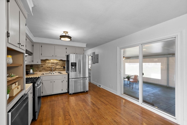 kitchen featuring backsplash, dark wood finished floors, light countertops, stainless steel appliances, and a sink