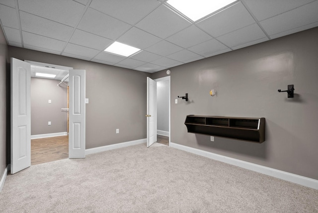 below grade area with a drop ceiling, baseboards, and carpet floors