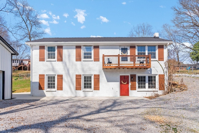 view of front facade with brick siding and a balcony