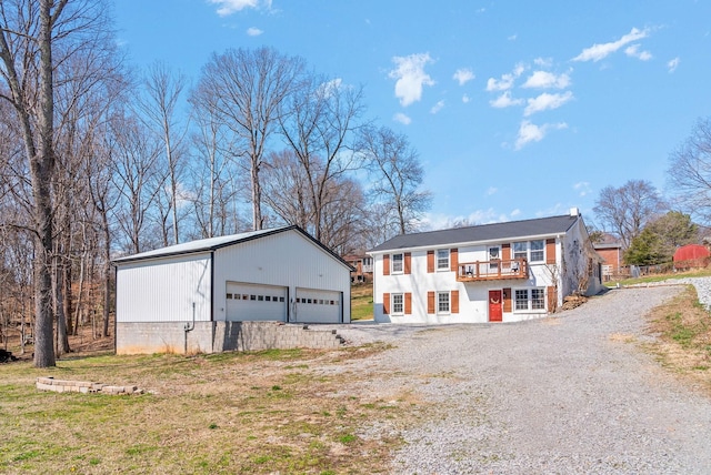 view of front of property with a detached garage, a balcony, and an outdoor structure