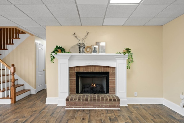 room details featuring a drop ceiling, baseboards, wood finished floors, and a fireplace