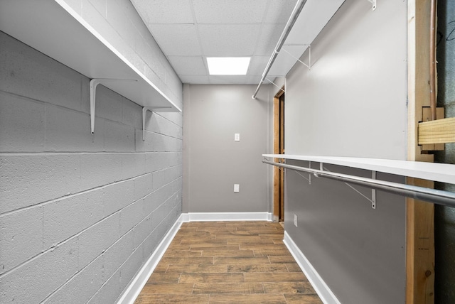 spacious closet with dark wood-style floors and a drop ceiling